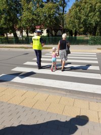 policjant WRD przeprowadza kobietę z dzieckiem przez ulicę