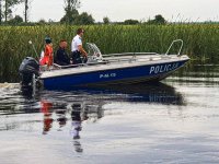 Policjanci patrolują rzekę w łodzi policyjnej.