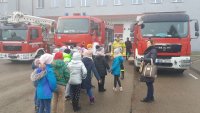 dzieci podchodzą z opiekunką do wozów strażackich