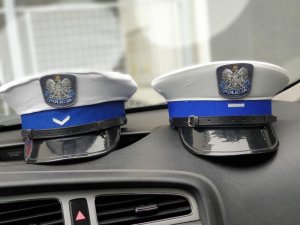 czapki policyjne ruchu drogowego leżące na desce rozdzielczej w radiowozie