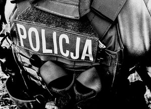 sylwetka mężczyzny z założoną kamizelką taktyczną z napisem POLICJA