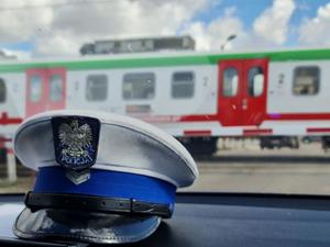 czapka policyjna ruchu drogowego, w tle przejeżdżający pociąg