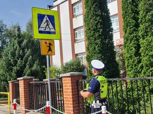 policjant ruchu drogowego sprawdza oznakowanie przejścia dla pieszych w rejonie szkoły
