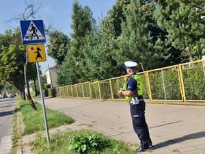 policjant ruchu drogowego sprawdza oznakowanie w rejonie szkoły