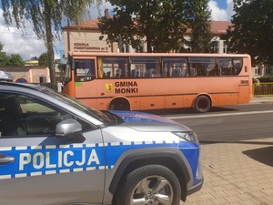 radiowóz w rejonie szkoły, w tle przejeżdżający autobus szkolny