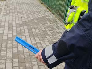 policjant trzyma w ręce niebieski odblask z napisem: Komenda powiatowa Policji w Mońkach