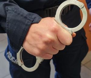 policjant trzyma kajdanki w ręce