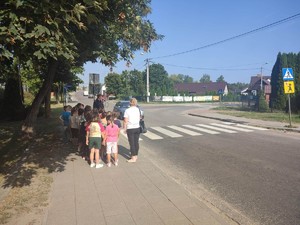 policjant wraz z dziećmi przechodzi przez jezdnię