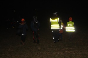 policjant z dziećmi idą wieczorową porą w odblaskach