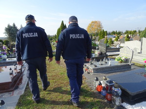 na zdjęciu umundurowani policjanci idący alejką na cmentarzu