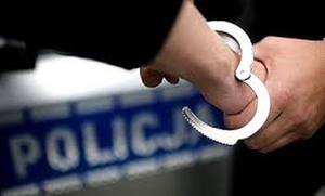 kajdanki na ręku, w tle napis policja
