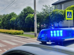 Radiowóz w pobliżu przejścia dla pieszych. W prawym górnym rogu zdjęcia - znak drogowy przejście dla pieszych
