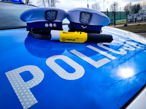czapki policyjne i urządzenie do pomiaru alkoholu w organizmie na masce radiowozu