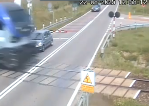 zdjęcie nagrania z kamery monitoringu. Widać na nim pociąg i pojazd za rogatkami