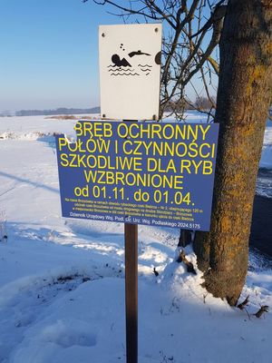 Na zdjęciu znajduje się tablica informacyjna na której widniej zapis obręb ochronny połów i czynności szkodliwe dla ryb wzbronione