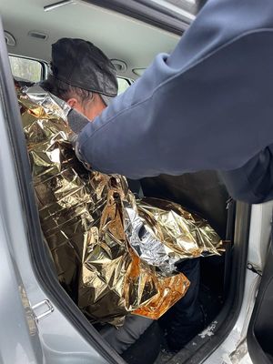 mężczyzna z założonym kocem termicznym siedzący w radiowozie