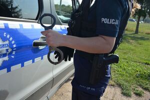 policjantka z kajdankami, w tle radiowóz
